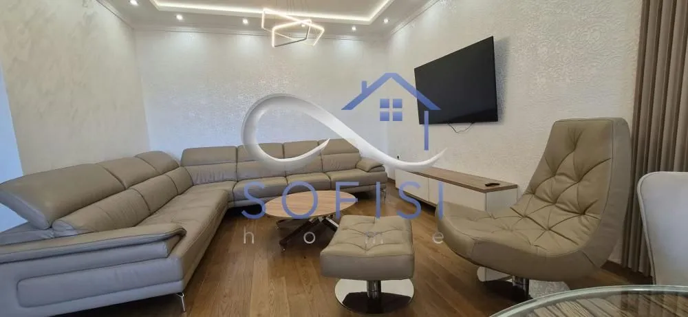 Living room with a sectional sofa, armchair, and wall-mounted TV.