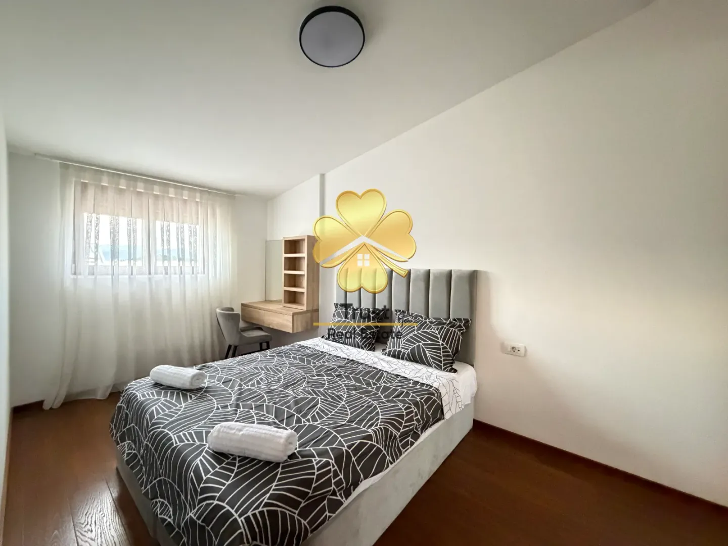 Bright and tidy bedroom with a double bed and a desk.
