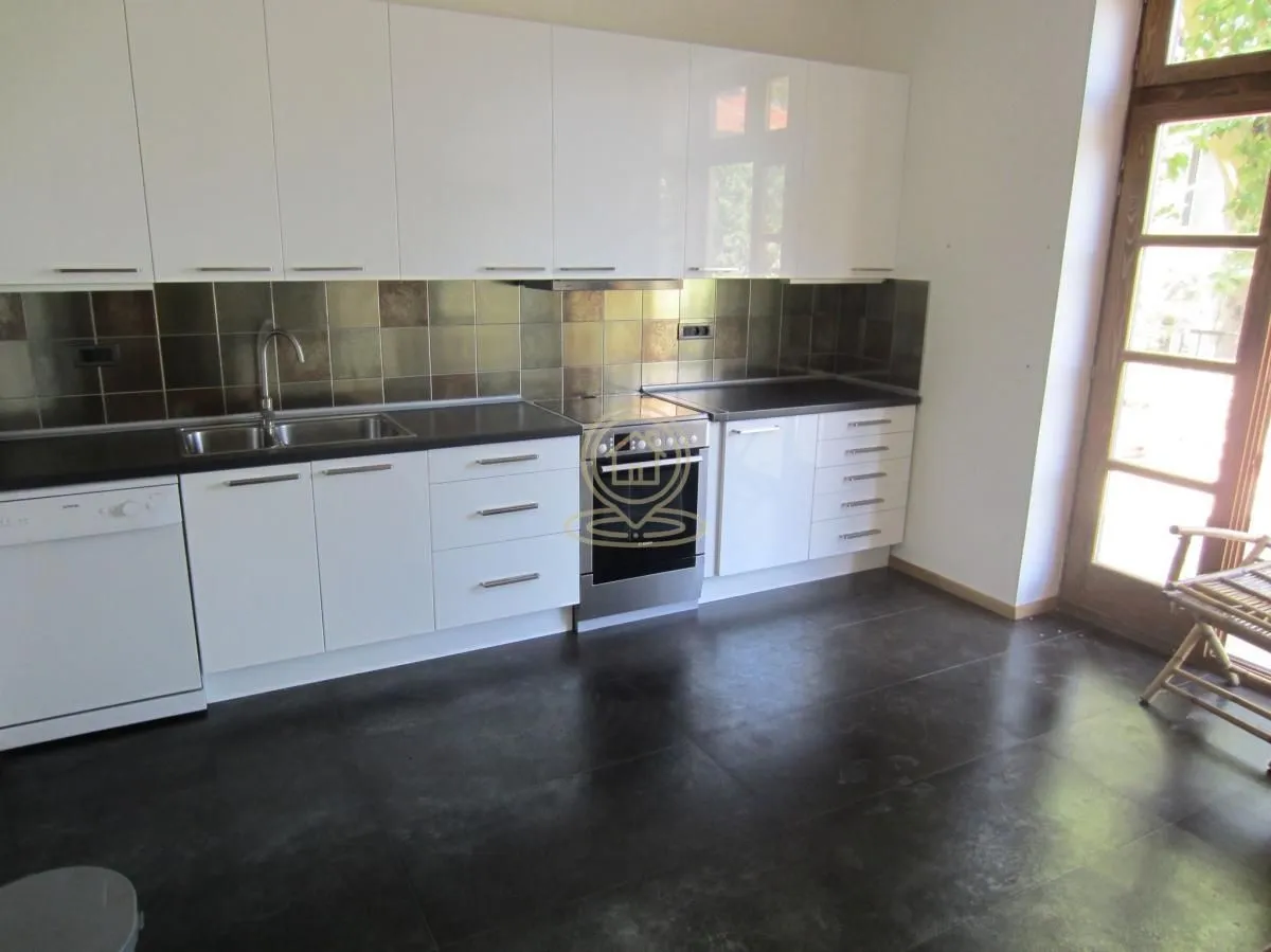 White kitchen with dark countertops and built-in appliances.