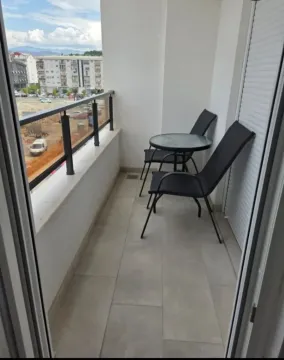 Small covered balcony with a table and two chairs. - image 2