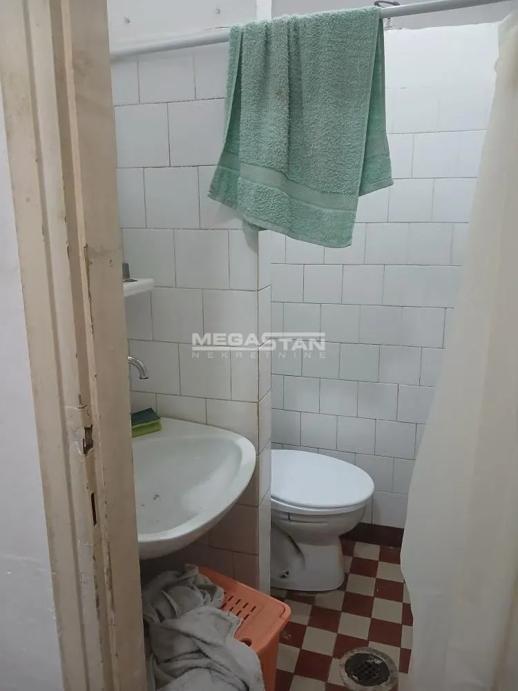 Pogled na starije kupatilo sa umivaonikom i toaletom.