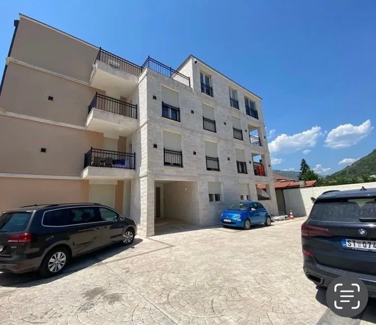 Exterior of an apartment building with a yard and parking area.
