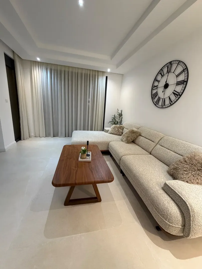 Modern living room with a sectional sofa, wooden coffee table, and a decorative wall clock.