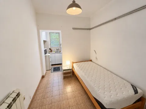 Small bedroom with a bed and a passage leading to the kitchen. - image 6
