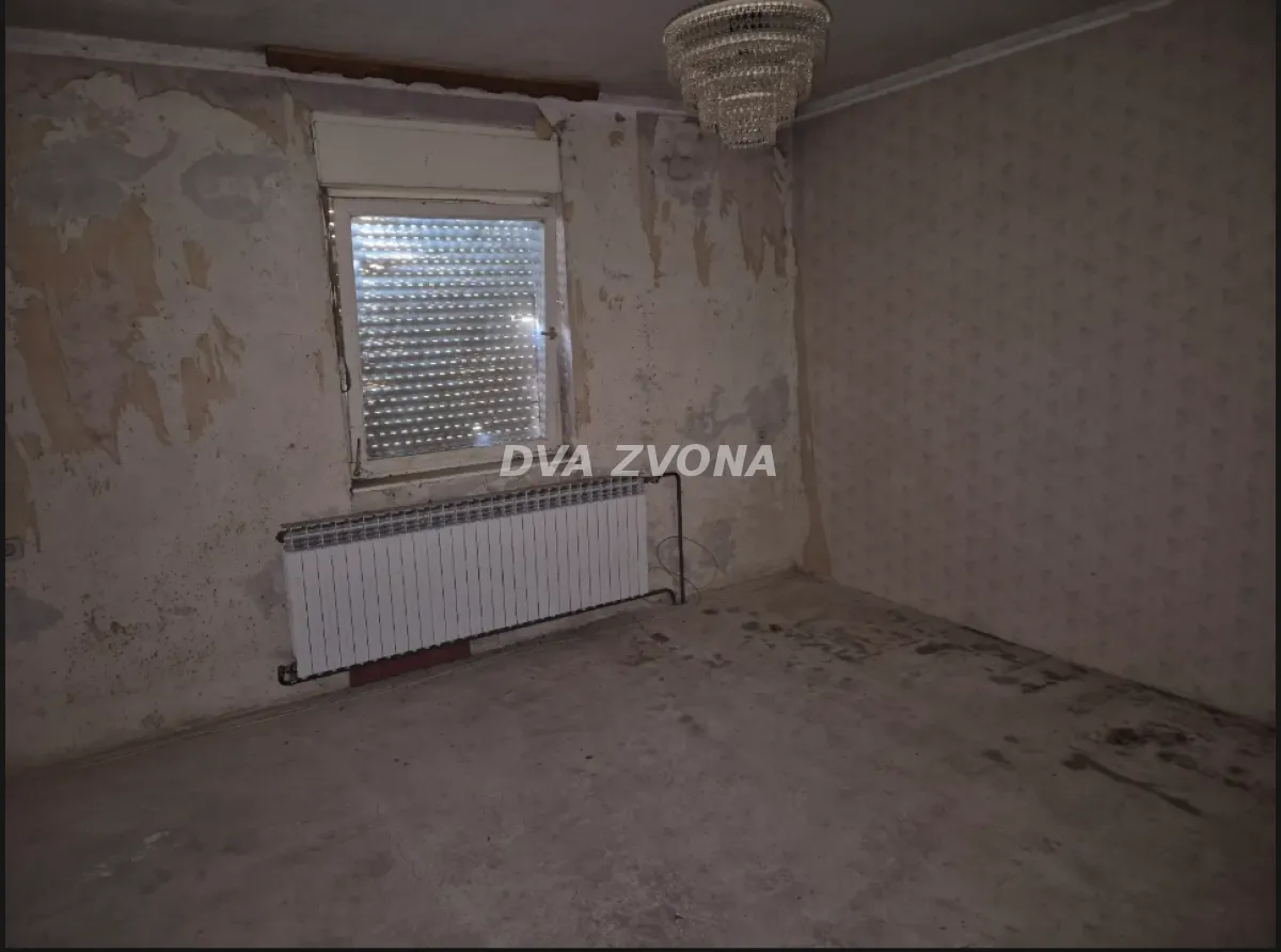 Prazna prostorija sa prozorom i radijatorom kojoj je potrebna adaptacija.
