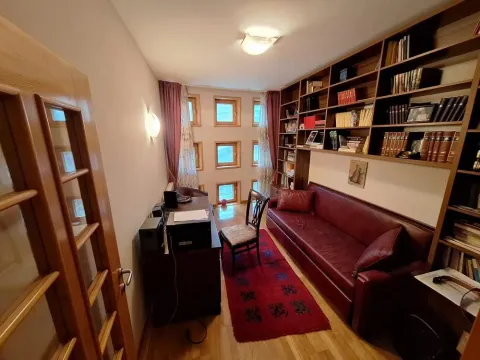 Dnevna soba sa velikom bibliotekom, radnim stolom i crvenom sofom. - image 16
