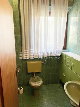 Smaller bathroom with green tiles, toilet and washbasin. - image 7
