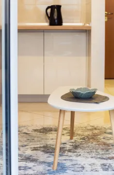 Small coffee table in the living room with a decorative bowl, overlooking the kitchen in the background. - image 6