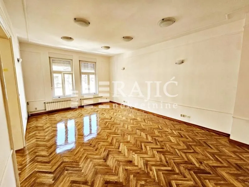 Empty spacious room with parquet flooring and white walls.