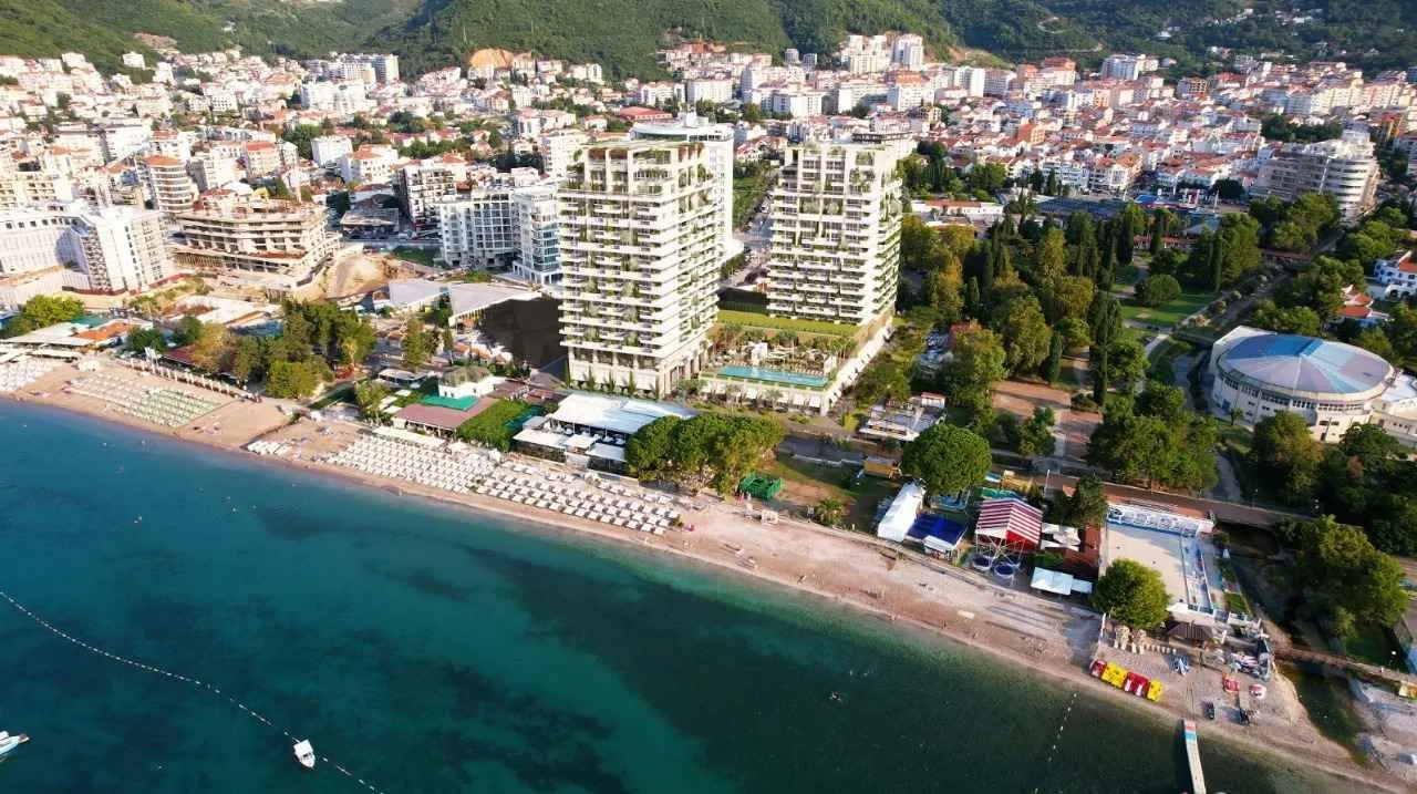 Pogled iz vazduha na obalu sa plažom i modernim zgradama u naselju.