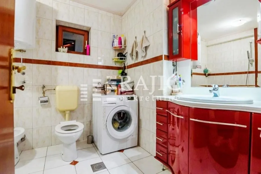 Bathroom with sanitary fixtures, washing machine, and red elements.