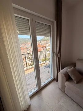 Pogled iz dnevne sobe na terasu sa gradskim pejzažom i brdima. - image 6