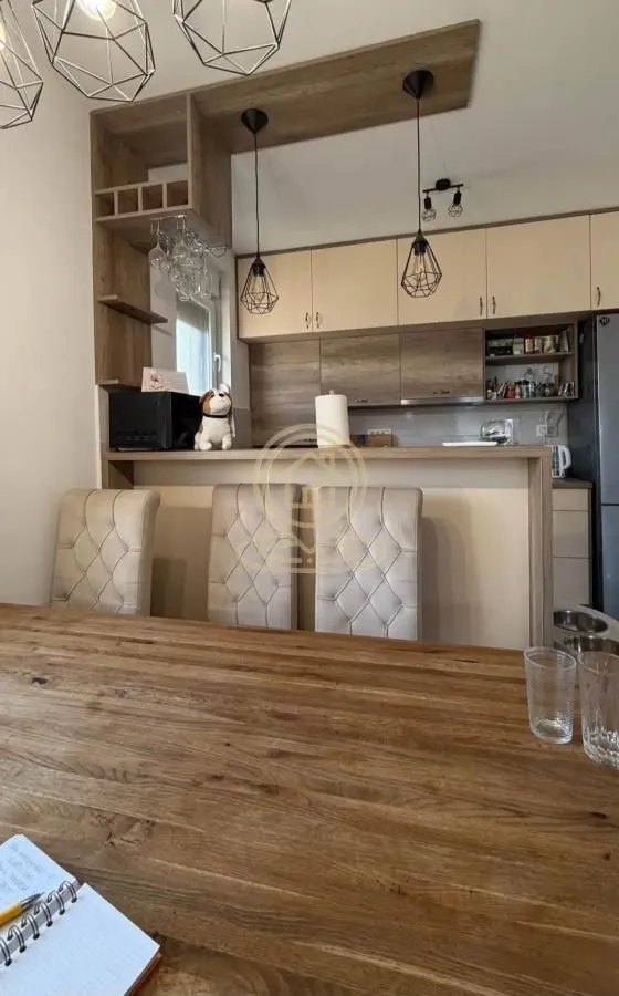 Kuhinja sa šankom i trpezarijskim stolom u prvom planu.