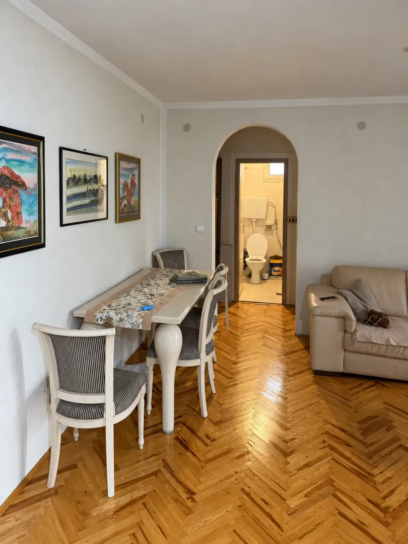 Living room with a dining table and a view of the bathroom through the archway.