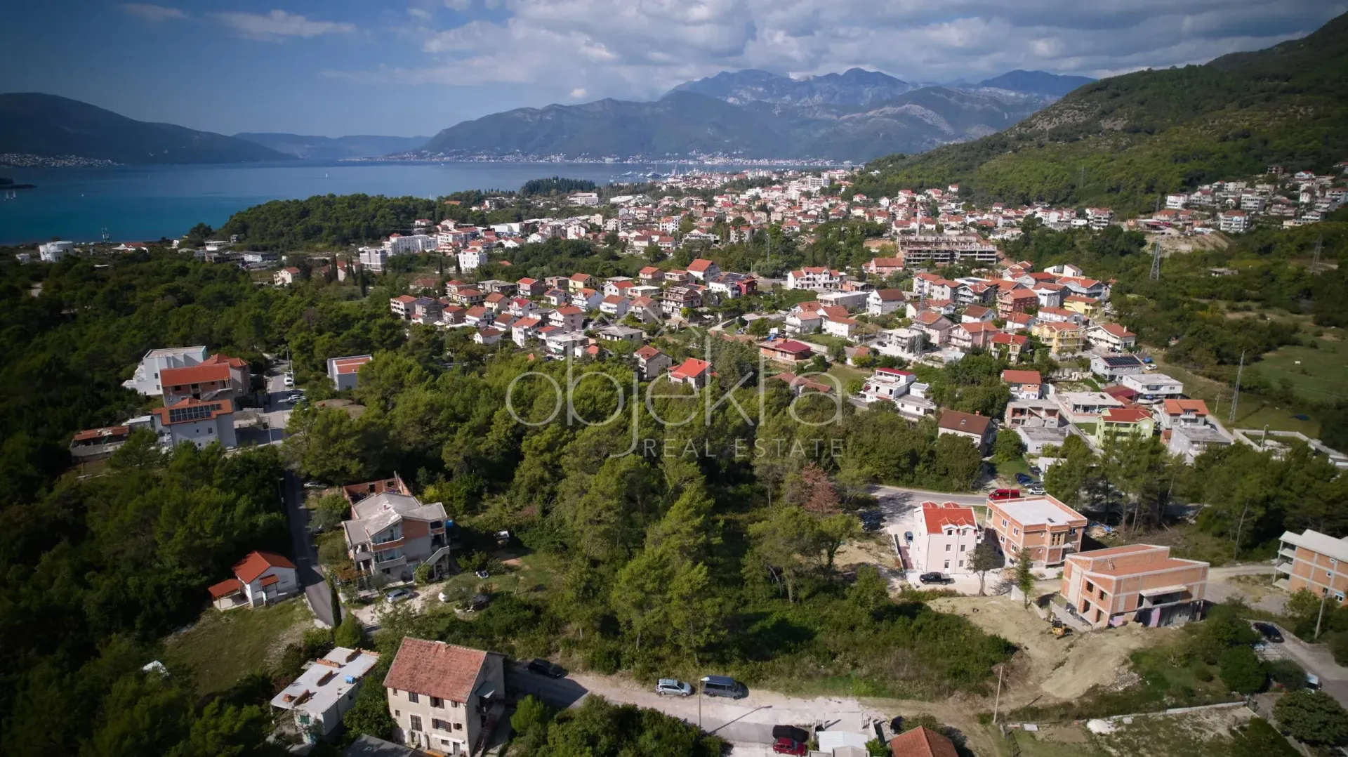 Pogled iz ptičje perspektive na naselje i more sa planinama u pozadini.