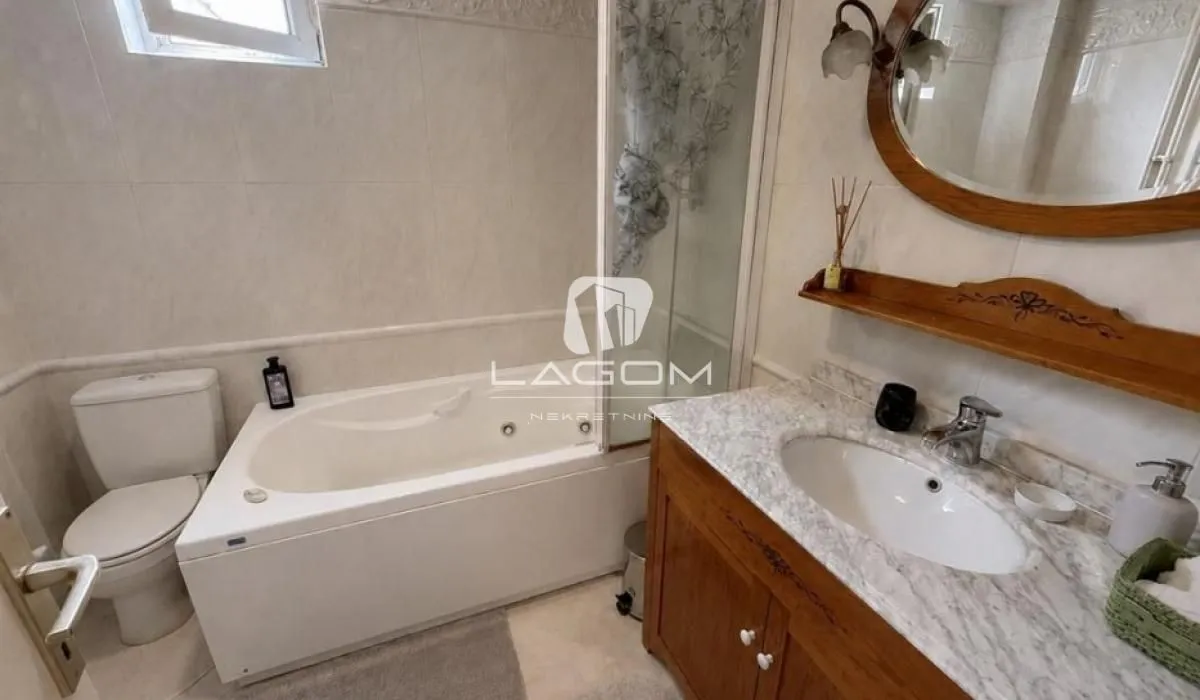 Bathroom equipped with a bathtub, toilet, and wooden vanity unit.