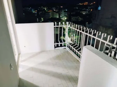 Osvijetljena terasa sa bijelom ogradom i pogledom na noćni grad. - image 8