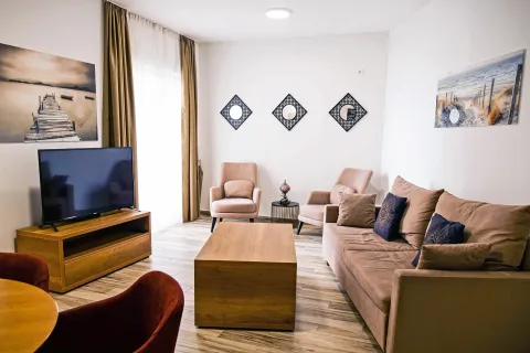 Dnevna soba sa garniturom, foteljama, TV-om i dekorativnim ogledalima na zidu. - image 13