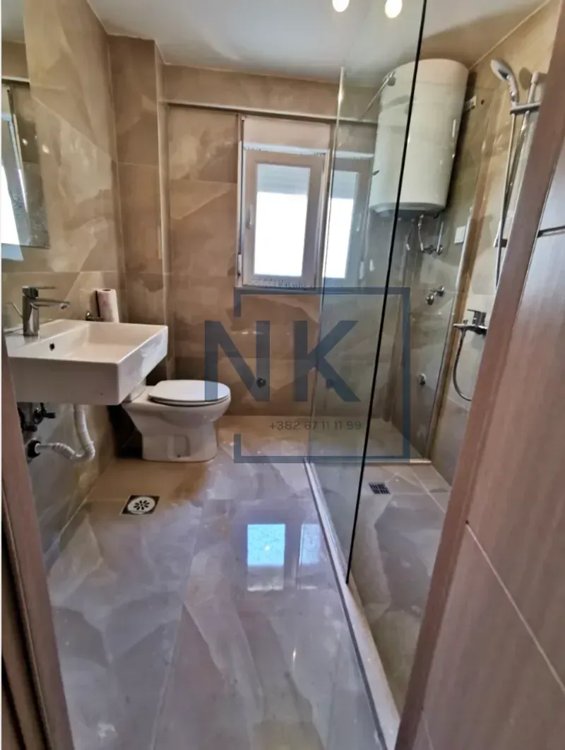 Modern bathroom with a walk-in shower, washbasin, and toilet.