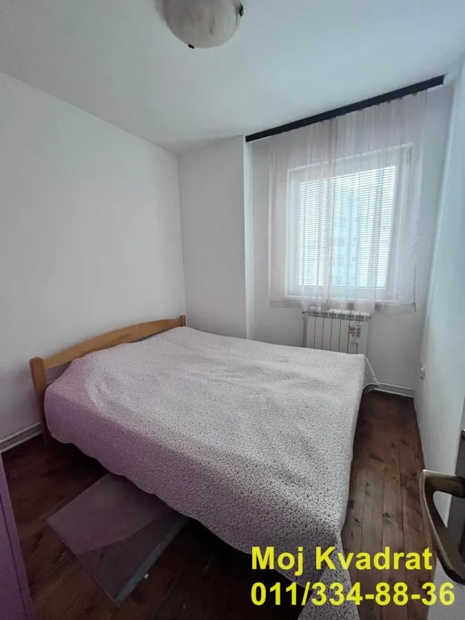 Manja spavaća soba sa bračnim krevetom i prozorom.