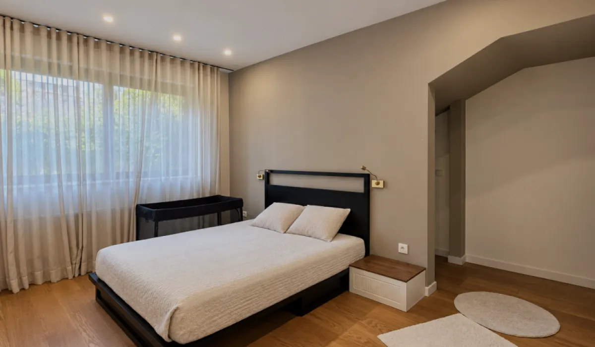 Modern bedroom with a double bed, large window, and curtains.