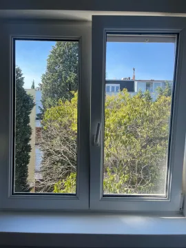 Pogled kroz prozor na okolno zelenilo i zgrade. - image 6