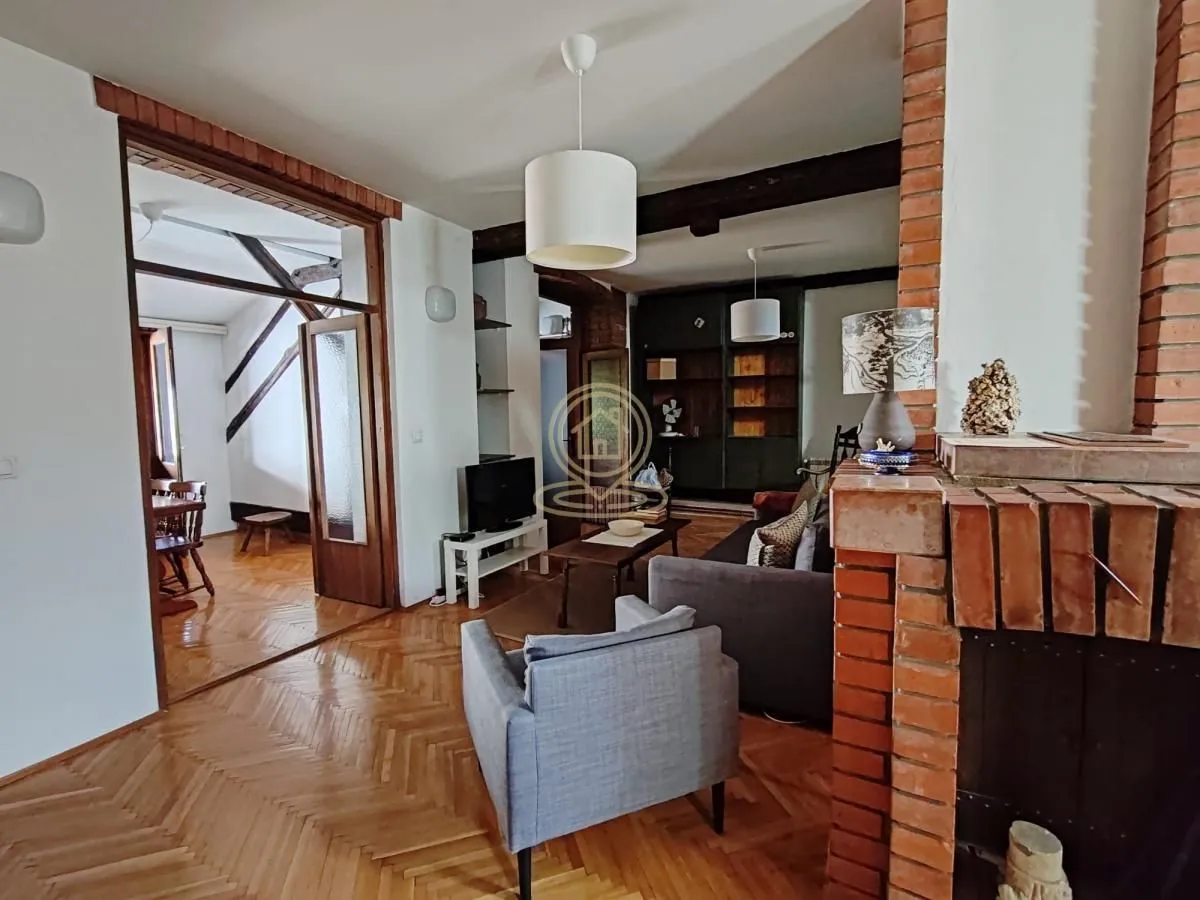 Living room with a fireplace, wooden floor and a view of the adjacent room.