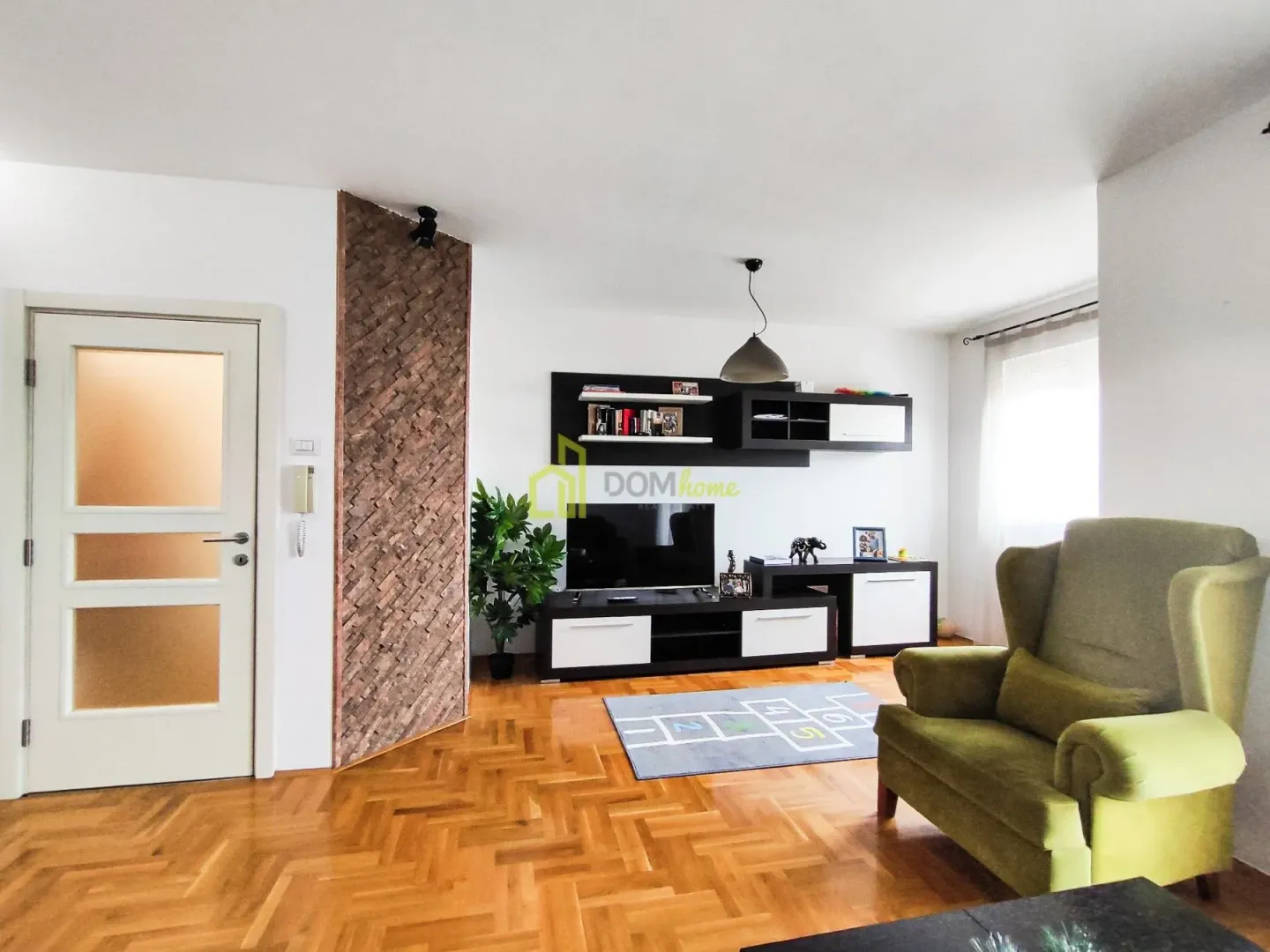 Living room with a sofa, TV unit, and wooden flooring.
