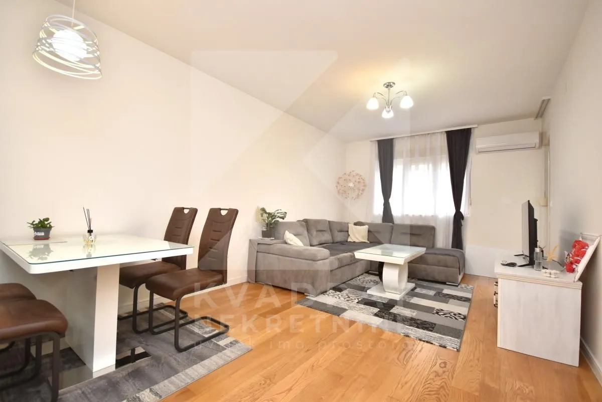 Living room with a sofa set, dining table and TV unit.