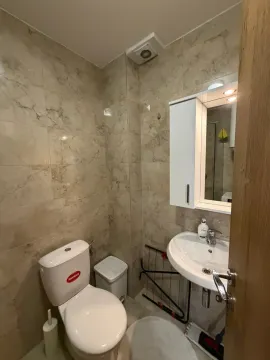 Small tiled bathroom equipped with a sink, mirror, and toilet. - image 5