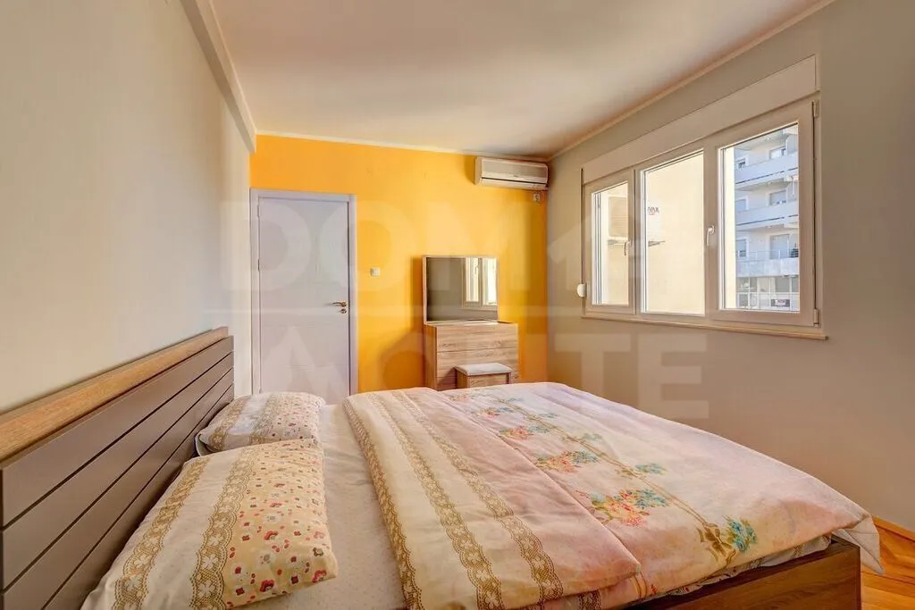 Furnished bedroom with a double bed, dresser, and window.