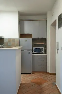 Smaller kitchen with grey cabinets and a refrigerator. - image 6