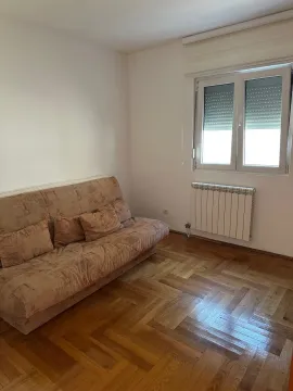 Living room with a sofa, parquet flooring, and a window. - image 10