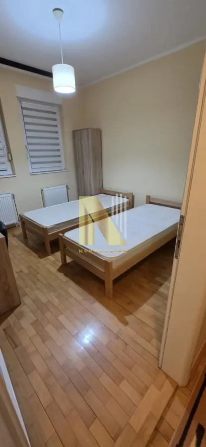 Spavaća soba sa dva drvena kreveta i ormarom.