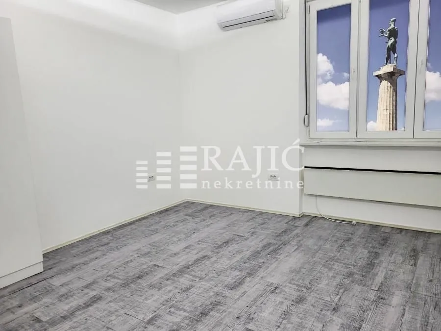 Empty room with grey laminate flooring and an air conditioner.