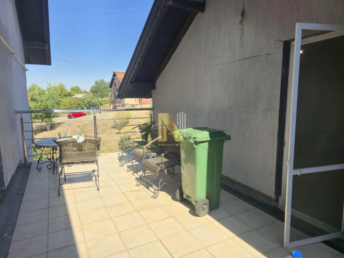 Prostrana popločana terasa sa garniturom za sedenje i pogledom na okolinu.