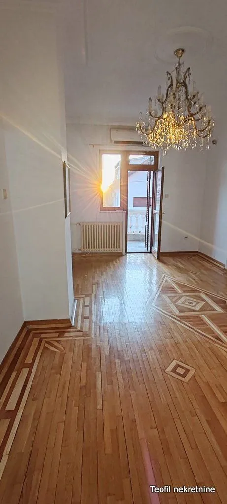 Empty room with parquet flooring, a chandelier, and balcony access.
