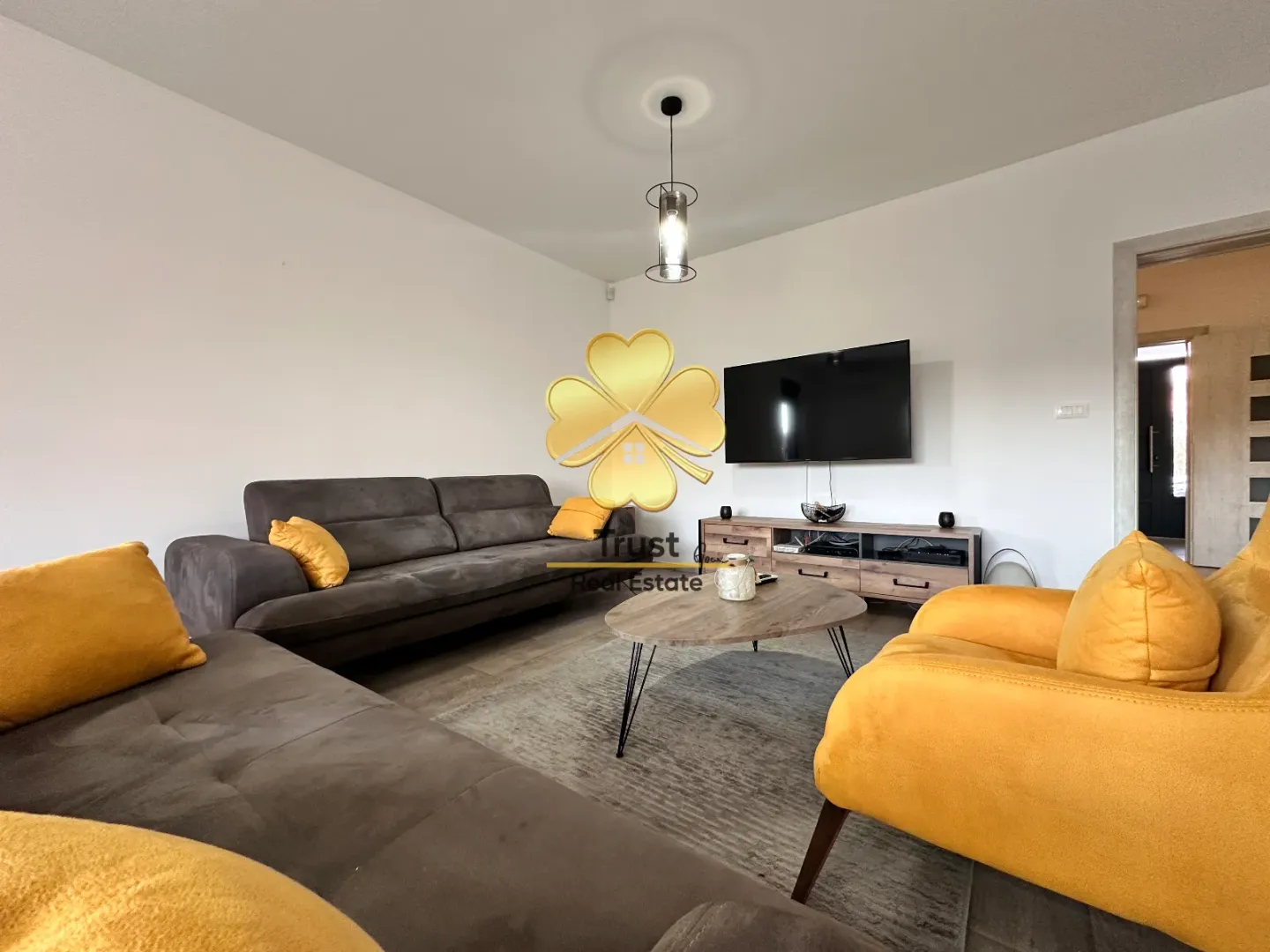 Furnished living room with sofa set and TV.
