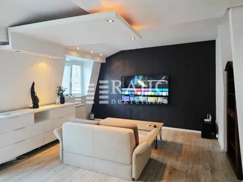 Dnevna soba sa garniturom, TV-om na zidu i spuštenim plafonom sa ugrađenom rasvetom. - image 5