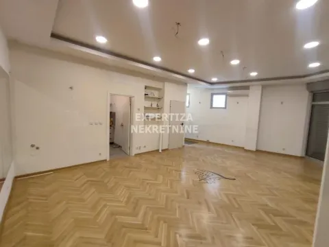 Spacious empty room with parquet flooring and a dropped ceiling with lighting. - image 3