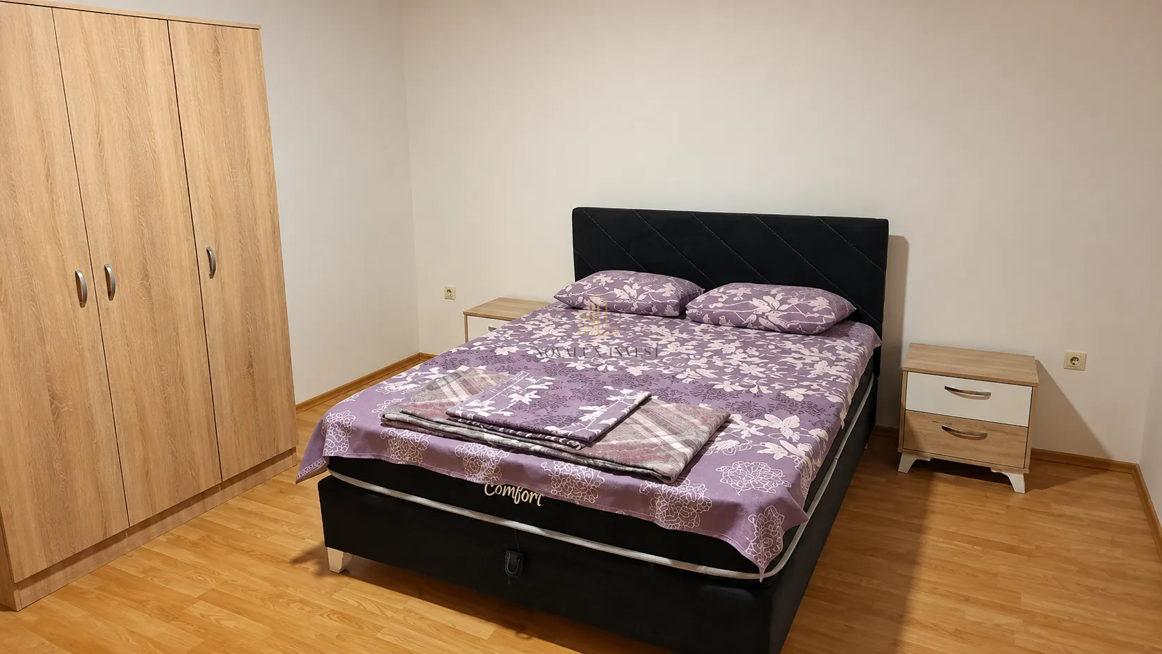 Namještena spavaća soba sa bračnim krevetom, ormarom i noćnim stočićima.