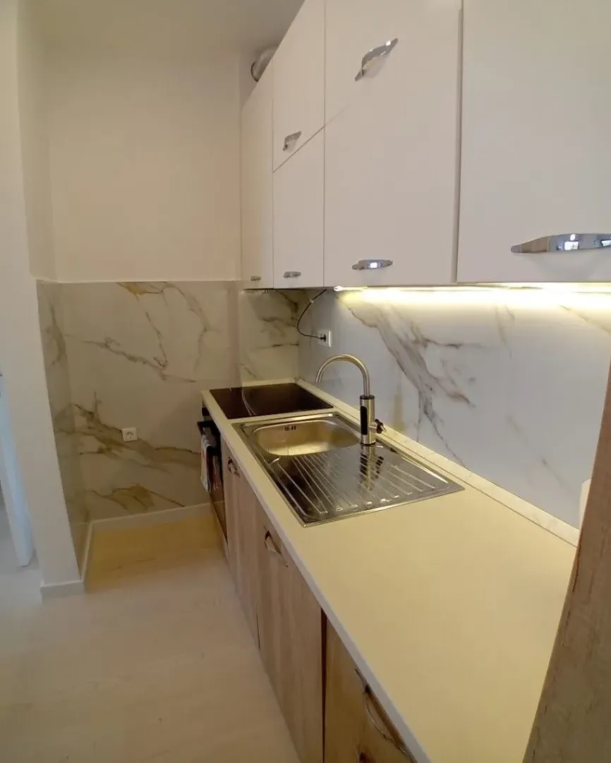 Modern kitchen with white cabinets, sink, and marble backsplash.