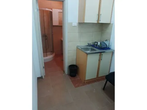 A small kitchen area with a sink next to the entrance of a bathroom with a shower. - image 10