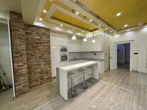 Modern kitchen with a breakfast bar, white cabinetry, and stone wall details. - image 3