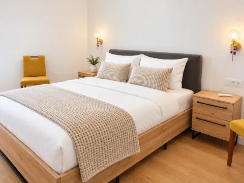 Furnished bedroom with a double bed, wooden nightstands, and yellow chairs. - image 10