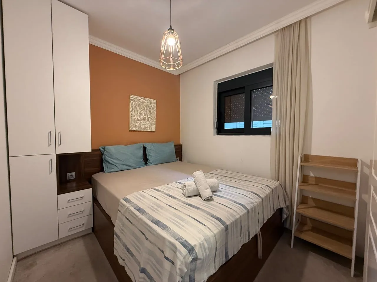 Uređena spavaća soba sa bračnim krevetom, garderoberom i ukrasnim detaljima.