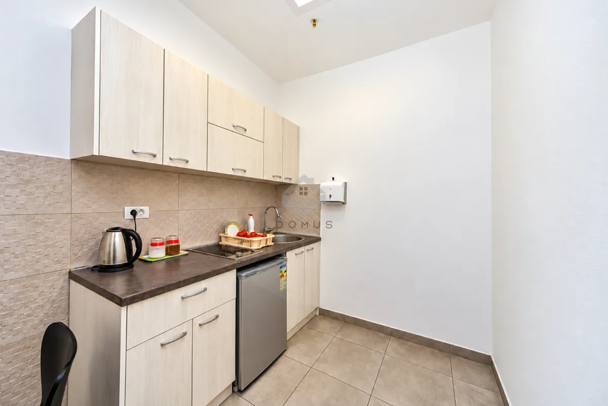 Small kitchen with a sink, refrigerator, and light-toned cabinets.