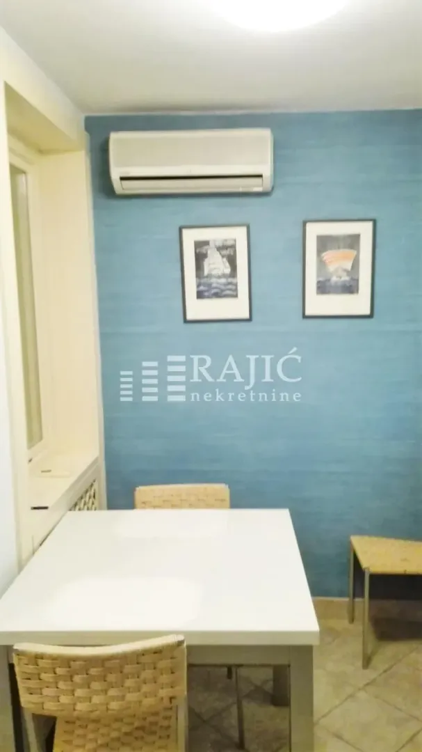 Trpezarija sa stolom, stolicama i plavim zidom.