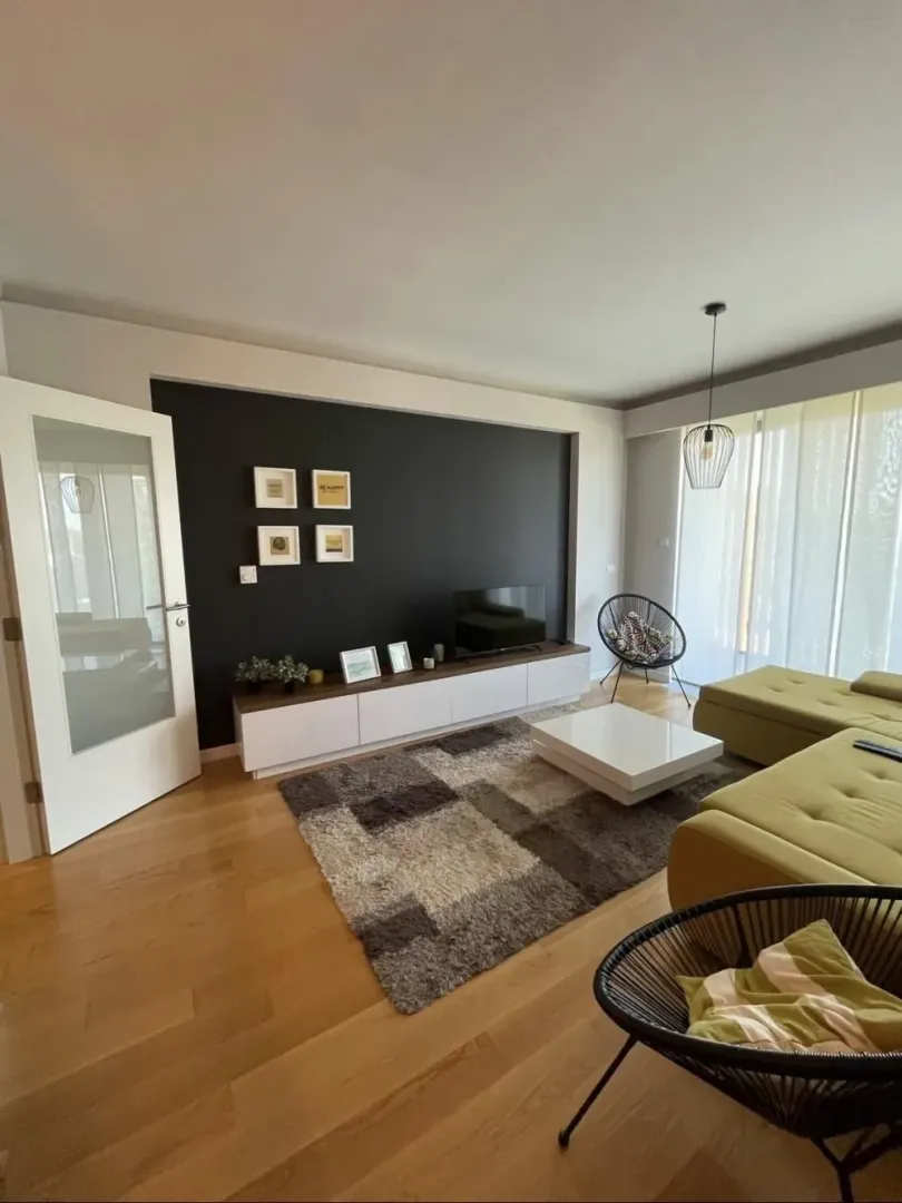 Living room with a sofa, television, and dining table in the background.
