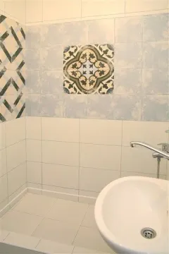 Kupatilo sa dekorativnim pločicama i bijelim umivaonikom. - image 15